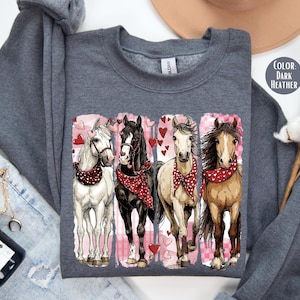 May include: Dark grey sweatshirt with a graphic of four horses wearing red bandanas and surrounded by hearts. The horses are white, black, tan, and brown. The design is on a dark grey crew neck sweatshirt.