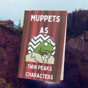 May include: A book cover with the text "Muppets as Twin Peaks Characters." The cover features a green Kermit the Frog illustration in a suit, set against a red and brown striped background. The book is set against a scenic background.