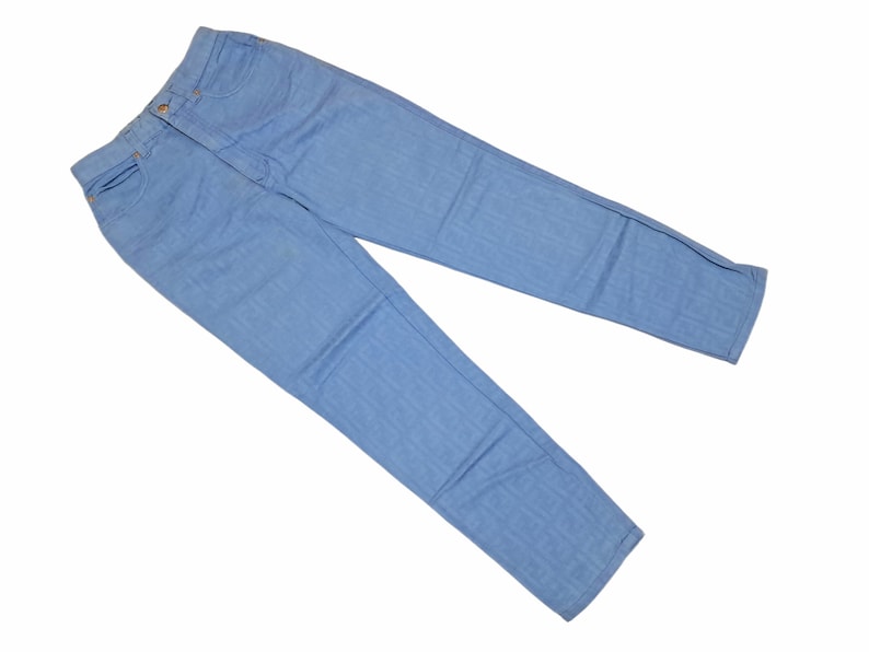 May include: A pair of light blue denim jeans. The jeans are laid flat on a white background.