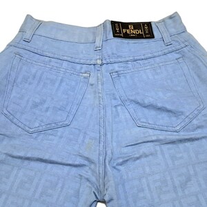 May include: Light blue denim jeans with a FENDI logo on the back pocket. The jeans have a faded look and are made of a soft, comfortable fabric.