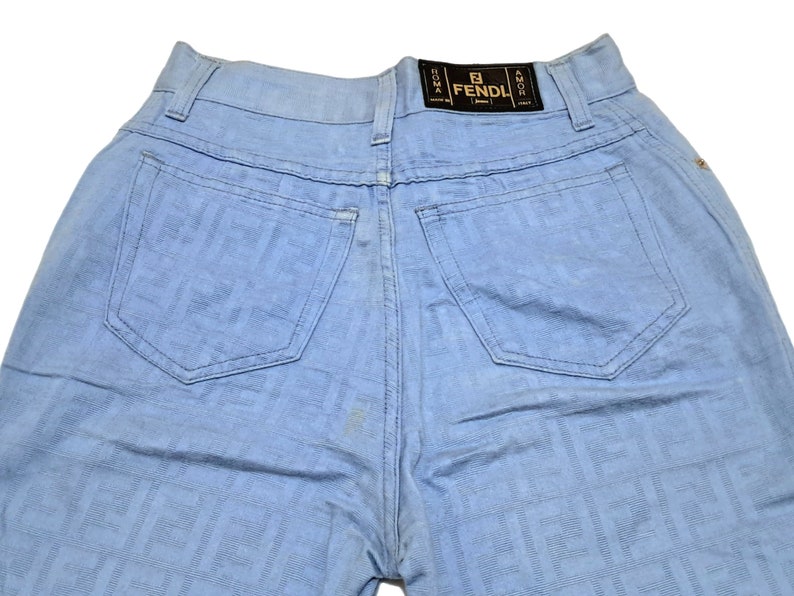 May include: Light blue denim jeans with a FENDI logo on the back pocket. The jeans have a faded look and are made of a soft, comfortable fabric.
