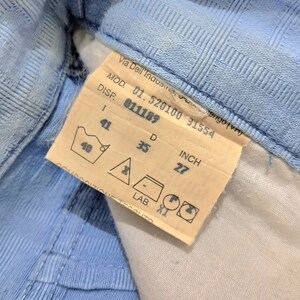 May include: A white tag with black text and a blue washing instruction symbol. The tag reads "Via Dell'Industria, tengo (vn) MOD. 01.520100 31554 DISP. 011189 I 41 D 35 INCH 27 40 - LAB. XI".