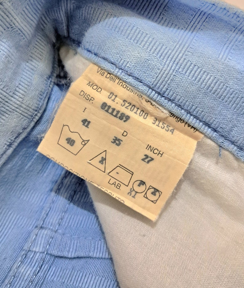 May include: A white tag with black text and a blue washing instruction symbol. The tag reads "Via Dell'Industria, tengo (vn) MOD. 01.520100 31554 DISP. 011189 I 41 D 35 INCH 27 40 - LAB. XI".