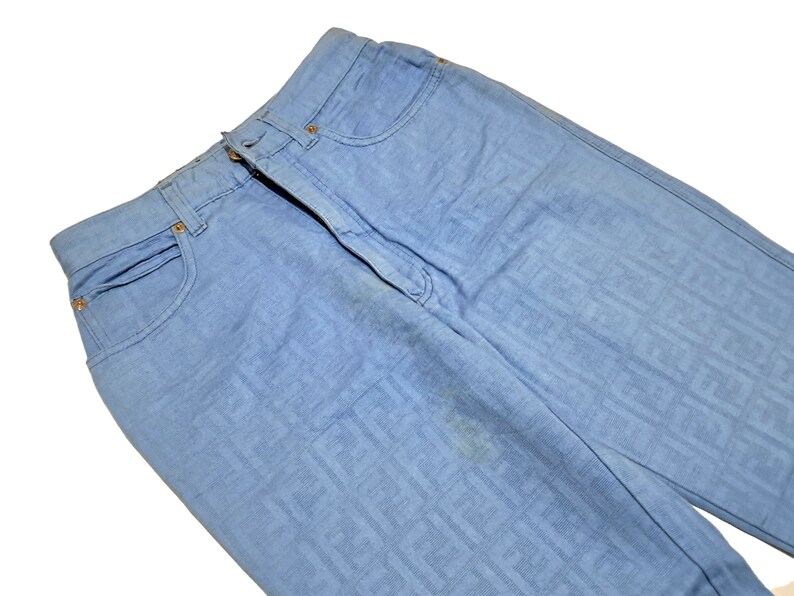 May include: Light blue denim jeans with a subtle patterned design. The jeans have a classic five-pocket style.