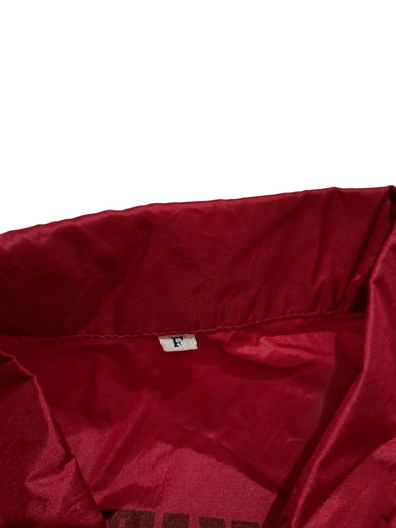 Peut inclure: Une veste rouge avec une &eacute;tiquette blanche sur laquelle est inscrit "F".