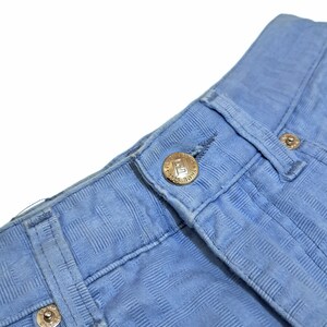 May include: Close-up of a pair of light blue jeans with a checkered pattern. The jeans have a button fly and a small metal button with the text "MADE IN USA" on it.