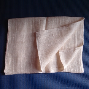 May include: A white, folded cloth napkin. The napkin is made of a soft, textured fabric.