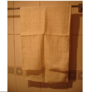 May include: A plain white hand towel hanging on a silver towel rack in a bathroom.