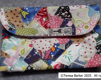 A beautiful patchwork fabric purse/pouch with two magnetic poppers on the front flap.  Fabric has been handmade