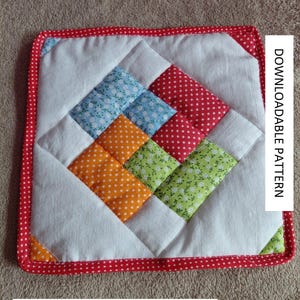 Könnte beinhalten: Quadratischer Patchwork-Quilt mit rotem Tupfenrand. Die Mitte zeigt ein Rautenmuster aus blauem Blumen-, roten Tupfen-, orangefarbenem Tupfen- und grünem Blumenstoff. Der Text "DOWNLOADABLE PATTERN" befindet sich auf der rechten Seite.