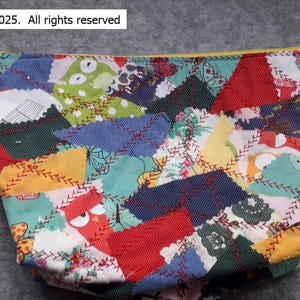 May include: A colourful patchwork fabric pouch with a yellow zipper. The fabric is made of different pieces of fabric sewn together in a random pattern. The pouch is decorated with embroidered owls and other designs.