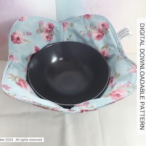 Può includere: Un copri ciotola in tessuto floreale blu e bianco con una ciotola nera all'interno. Il tessuto ha un motivo floreale rosa. Il testo "DIGITAL DOWNLOADABLE PATTERN" è stampato sul lato destro dell'immagine.