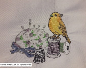 Machine embroidered tea towel with a beautiful canary sat on a cotton reel next to a pin cushion.   Brighten your kitchen