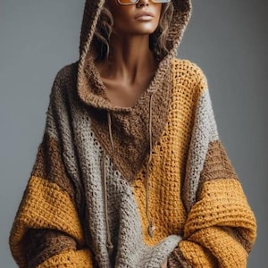 May include: A hooded crochet sweater in shades of brown, tan, and mustard yellow. The oversized sweater features a drawstring neckline and large sleeves. The model is wearing large square sunglasses.