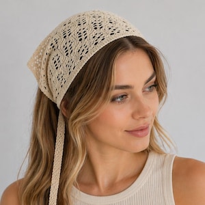 Puede incluir: Un pañuelo para la cabeza beige, de tejido abierto, con forma cuadrada y largas cintas colgantes. La prenda para la cabeza está hecha de un material delicado y calado. El pañuelo se lleva en la cabeza y se ata en la nuca.