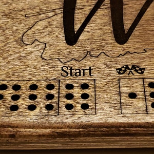 May include: A wooden game board with a race track design. The board has a brown stain and black dots. The text "Start" is printed on the board. The board is made of wood and has a natural finish.