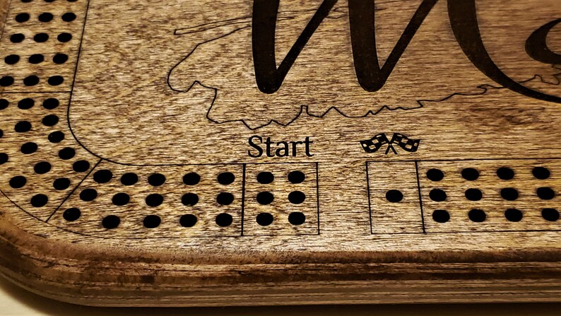 May include: A wooden game board with a race track design. The board has a brown stain and black dots. The text "Start" is printed on the board. The board is made of wood and has a natural finish.