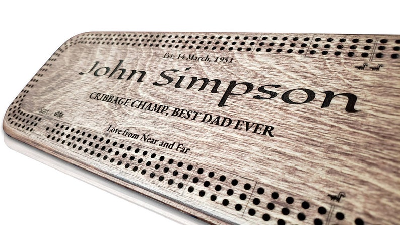 May include: A personalised wooden cribbage board with the inscription "Est. 14 March, 1951 John Simpson Cribbage Champ, Best Dad Ever Love from Near and Far".