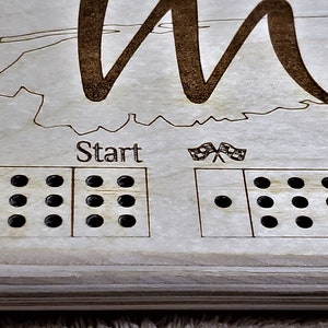 May include: A wooden game board with a map of a state and the word "Start" printed on it. The board has a grid of holes for playing a game.