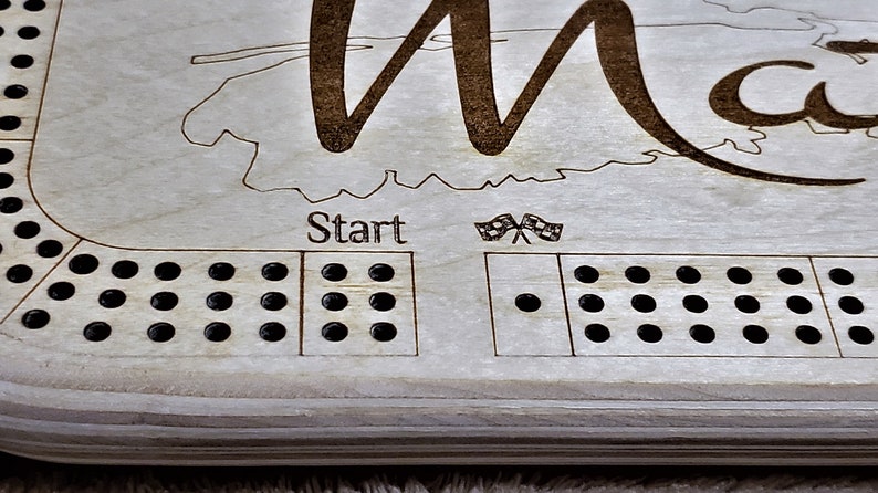 May include: A wooden game board with a map of a state and the word "Start" printed on it. The board has a grid of holes for playing a game.