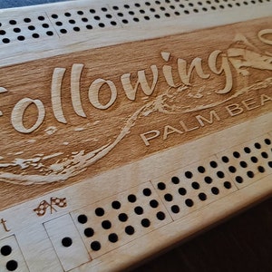 May include: A wooden game board with the words "Following Seas Palm Beach" engraved on it. The board has a grid of holes and a start space with a chequered flag.