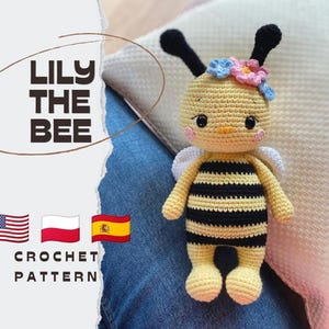Könnte beinhalten: Eine handgefertigte Häkelpuppe in Form einer Biene namens Lily the Bee mit gelb-schwarzen Streifen, schwarzen Fühlern, weißen Flügeln und einem Kranz aus kleinen blauen und rosa Blumen. Der Text LILY THE BEE CROCHET PATTERN steht auf der linken Seite.