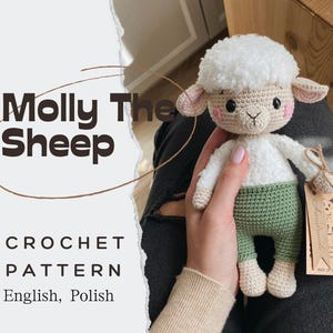 Può includere: Un giocattolo di pecora bianca all'uncinetto con pantaloni verdi, che tiene un'etichetta che dice "LKA Fatto a mano in Polonia". Il giocattolo è tenuto dalla mano di una persona. L'immagine include il testo "Molly The Sheep Crochet Pattern English, Polish".