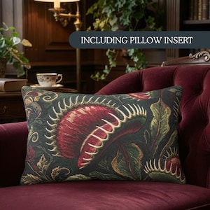 May include: A rectangular throw pillow featuring a dark green fabric with a woven pattern of red and green Venus flytrap plants. The pillow includes a pillow insert and displays the text INCLUDING PILLOW INSERT across the top portion.
