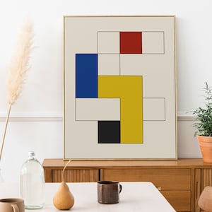 May include: Abstract geometric art print with a gold frame. The print features a white background with overlapping squares in red, yellow, blue, and black.