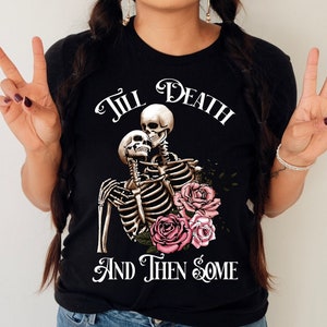 May include: Black t-shirt with a graphic of two skeletons embracing, surrounded by pink flowers. The text "Till Death And Then Some" is printed below the skeletons.