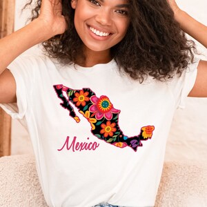 May include: A white t-shirt featuring a floral design of the outline of Mexico. The text "Mexico" is printed in pink below the design.