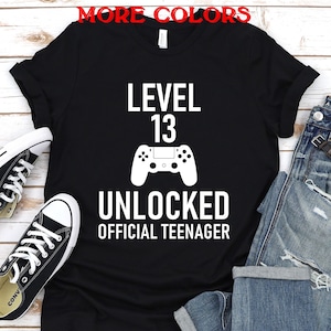May include: Black t-shirt with white text that reads "Level 13 Unlocked Official Teenager" and a white video game controller graphic.