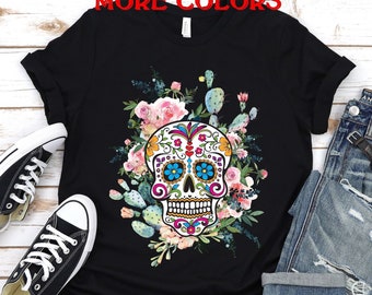 May include: Black t-shirt with a colorful sugar skull design surrounded by pink and white flowers and green cactus plants.
