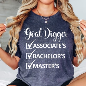 May include: A dark gray t-shirt with the text "Goal Digger" and a checklist with the following items: Associate's, Bachelor's, Master's.