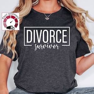 May include: A dark gray t-shirt with the text "DIVORCE survivor" printed in white.