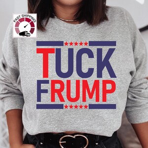 May include: Gray sweatshirt with the text "TUCK FRUMP" in red and blue letters. The text is surrounded by a blue and white striped border with five red stars on each side.