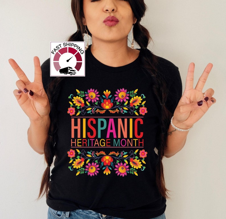 May include: Black t-shirt with a colorful floral design and the text "HISPANIC HERITAGE MONTH".