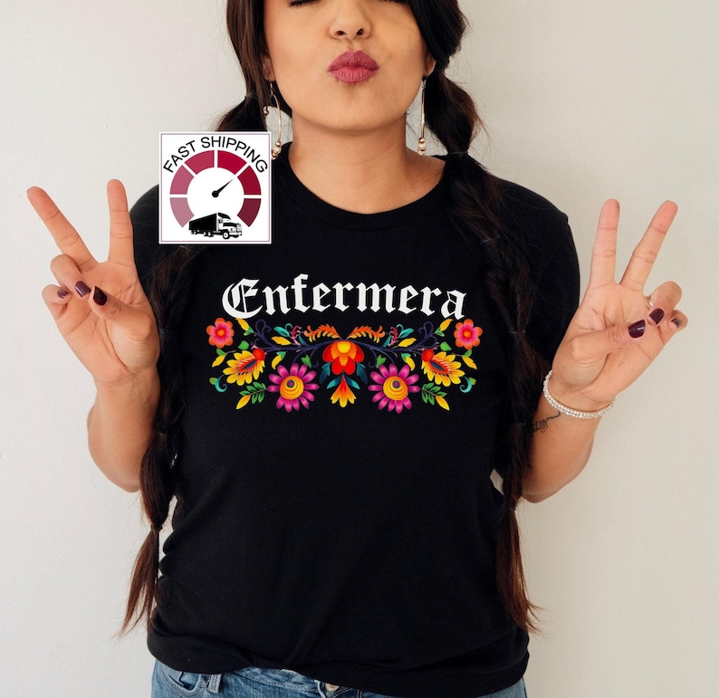 May include: Black t-shirt with the word "Enfermera" in white gothic lettering and a colorful floral design below.