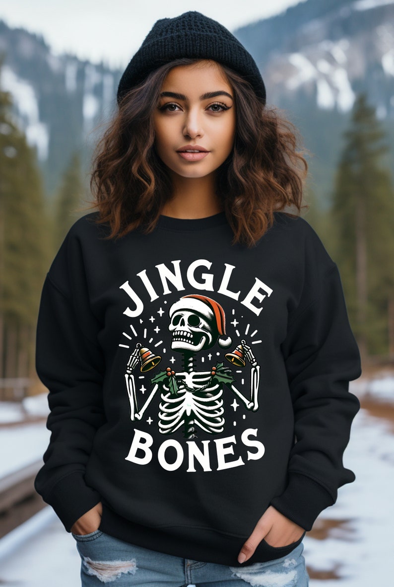 May include: Black sweatshirt with a white graphic of a skeleton wearing a Santa hat and holding jingle bells. The text "Jingle Bones" is printed below the skeleton.