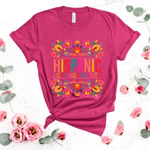 May include: Pink t-shirt with a floral design and the text "Hispanic Heritage Month" in colorful letters.