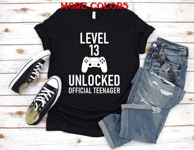 May include: Black t-shirt with white text that reads "Level 13 Unlocked Official Teenager" and a white video game controller graphic.