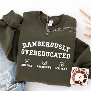 May include: A dark green sweatshirt with the text "Dangerously Overeducated" and checkmarks next to the words "Diploma", "Bachelor's", and "Master's".