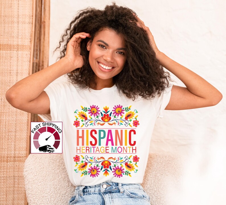 May include: White t-shirt with a colorful floral design and the text "HISPANIC HERITAGE MONTH".