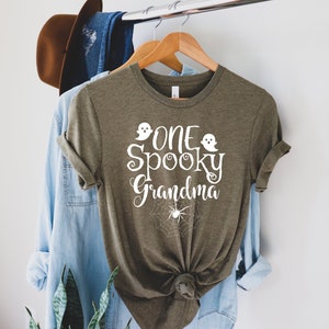 May include: A green t-shirt with the text "One Spooky Grandma" in white with two ghost and spider web graphics.