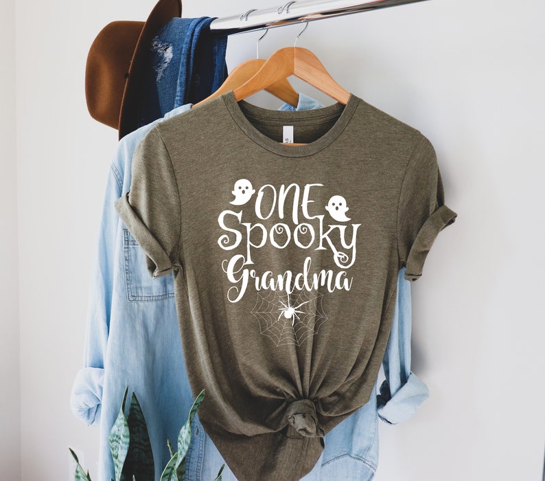 May include: A green t-shirt with the text "One Spooky Grandma" in white with two ghost and spider web graphics.