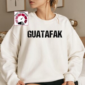May include: White sweatshirt with the text "GUATAFAK" printed in black.