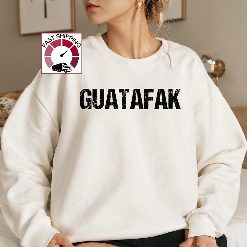 May include: White sweatshirt with the text "GUATAFAK" printed in black.