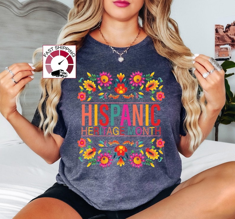 May include: A dark gray t-shirt with a colorful floral design and the text "HISPANIC HERITAGE MONTH".