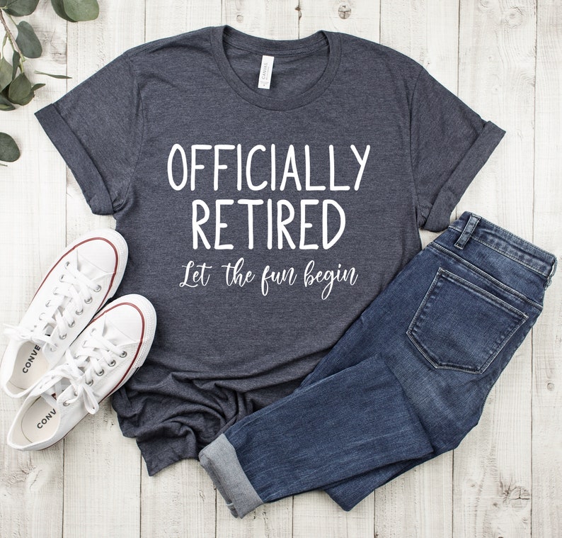 Puede incluir: Una camiseta gris oscuro jaspeada con el texto "Officially Retired Let the fun begin" en blanco.