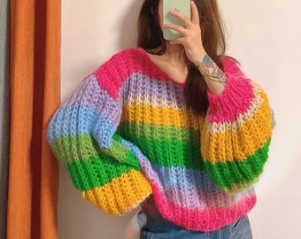 Könnte beinhalten: Ein regenbogenfarbener gestrickter Pullover mit langen Ärmeln und einer lockeren Passform.